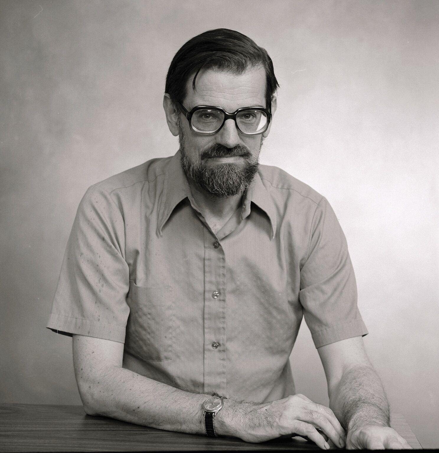 Nobel winning economist with beard sitting at table wearing glasses