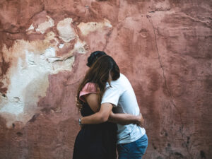 Couple hugging against textured red wall