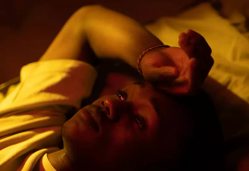 Man lying down, looking reflective in dim red light