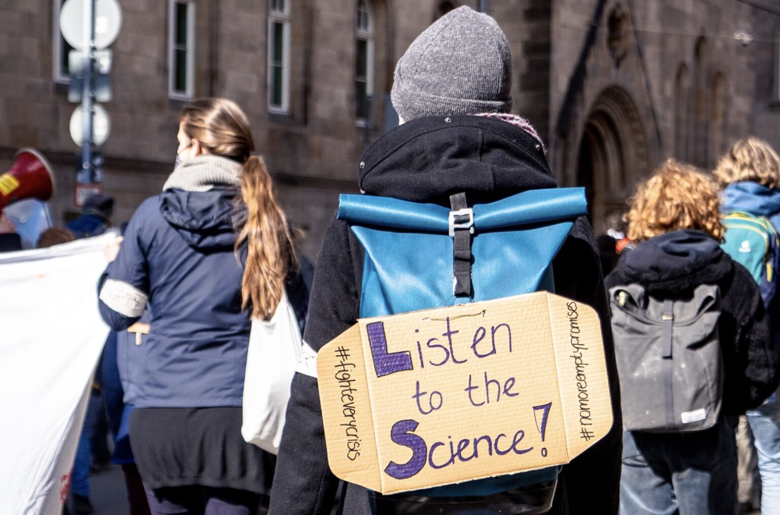 Protester with 'Listen to the Science!' sign at rally