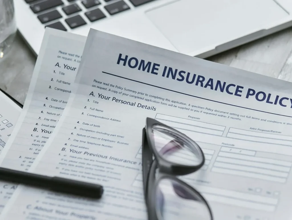 Home insurance policy documents with glasses on desk