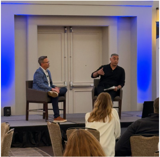 Two men discussing on stage at a conference.